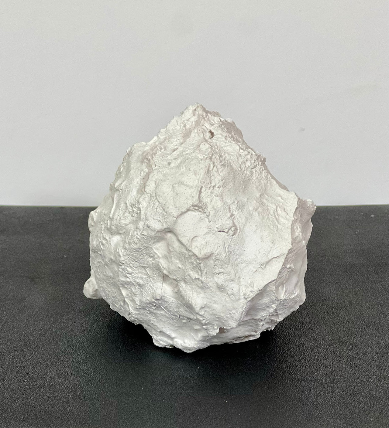 Not Vital – Schneeball, Gips-Skulptur, ca. 8 cm Durchmesser, Frontansicht auf dunklem Hintergrund.